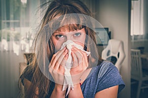 Sick woman with flu or cold sneezing into handkerchief