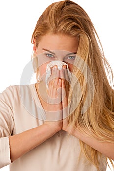 Sick woman with flu and fever blowing nose in tissue isolated over white background.