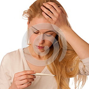 Sick woman with flu and fever looking in thermometer isolated over white background.