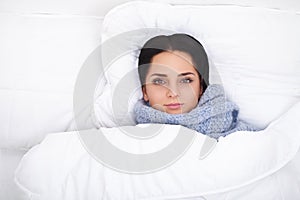 Sick Woman. Flu. Girl with cold lying under a blanket holding a