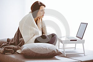 Sick woman with flue sitting at home consulting her doctor via internet