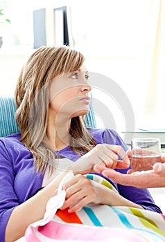 Sick woman with glass of water lying on a sofa