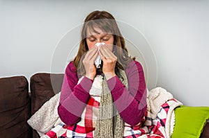 Sick woman having flu and blowing her runny nose