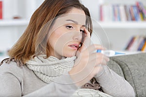 sick woman holding thermometre