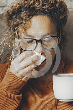 Sick woman at home blowing nose and take care of influenza virus disease. One female people using paper tissue and drink herbal