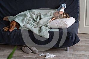 Sick woman at home lying in bed with her Vizsla dog, suffering from allergy, flu symptom, fever