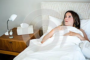 sick woman lying in bed looking unwell