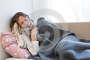 Sick woman lying in bed under plaid, trembles, tries to warm herself, having flu symptoms