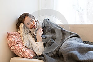 Sick woman lying on sofa and trembles, tries to warm herself ,having flu symptoms, feels cold.Virus