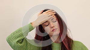 Sick woman measuring her temperature. The girl puts her hand to her forehead and checks how she feels.