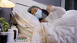 Sick woman in medical mask feeling cold and suffering from virus disease and fever in bed, coronavirus covid-19 pandemic concept