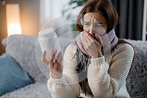 Sick woman with pills on sofa