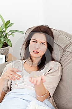 Sick woman showing a pill to the camera