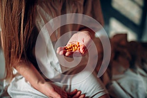 Sick woman sitting on hospital bed, drugs in hand