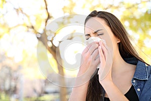 Sick woman sneezing covering nose in a park