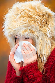 Sick woman sneezing in tissue outdoor