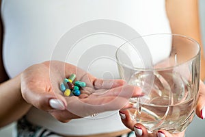 sick woman suffering from insomnia or headache and taking sleeping pills with glass of water.