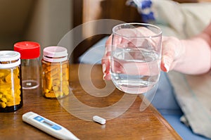 Sick woman taking a glass of water for medication