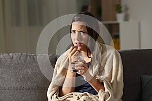 Sick woman taking painkiller pill looking at camera photo