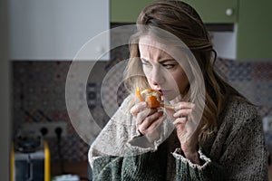 Sick woman trying to sense smell of fresh tangerine orange, has symptoms of Covid-19, corona virus photo