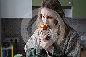 Sick woman trying to sense smell of fresh tangerine orange, has symptoms of Covid-19, corona virus