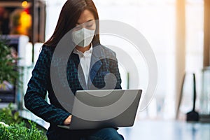 A sick woman wearing protective face mask, using laptop computer for Healthcare and Covid-19 concept