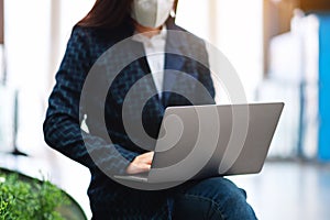 A sick woman wearing protective face mask, using laptop computer for Healthcare and Covid-19 concept