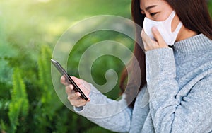 A sick woman wearing protective face mask, using mobile phone for Healthcare and Covid-19 concept