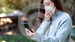 A sick woman wearing protective face mask, using mobile phone for Healthcare and Covid-19 concept