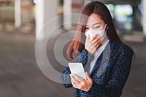 A sick woman wearing protective face mask, using mobile phone for Healthcare and Covid-19 concept