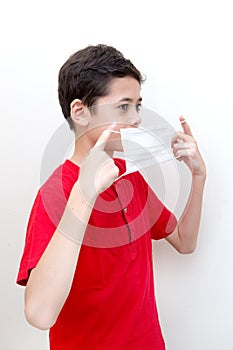 Sick young boy clutches his throat with face mask on.