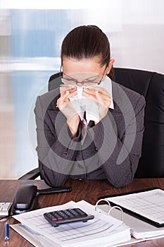 Sick young businesswoman blowing her nose