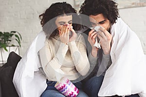 sick young couple blowing noses into napkins