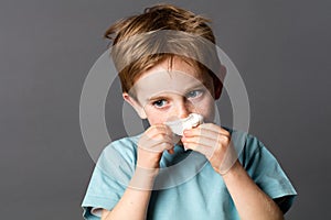 Sick young kid using a tissue after cold or spring allergies photo