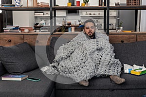 Sick young man being wrapped in plaid