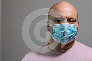 Sick young man with medical protective face mask illustrates pandemic coronavirus disease on blurred background. Covid-19 outbreak