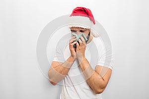 Sick young man in red hat stands and sneezes in napkin. He is ill. Guy in unhappy. Isolated on white background.
