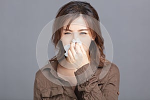 Sick young woman  blowing her nose