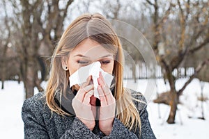Sick young woman blowing her nose