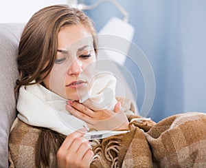 Sick young woman checking temperature