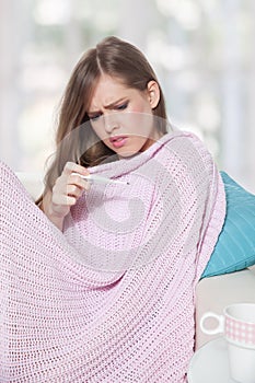 Sick young woman checking a thermometer