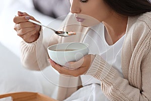 Sick young woman eating soup to cure flu
