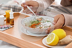 Sick young woman eating soup to cure flu