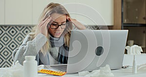 Sick young woman in eyeglasses sit at office homa desk rubs temple, closed eyes while getting sick and taking cure at