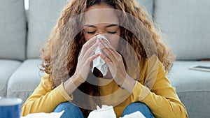 Sick young woman with flu or an allergy sneezing in a tissue and blowing nose. Ill girl caught a bad cold showing