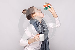 Sick young woman holding cup with tea, many pills, antibiotics.