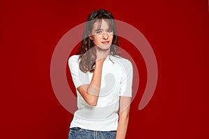 Sick young woman holding neck, suffering pain throat, tonsillitis, hard to swallow, voice loss on red studio background