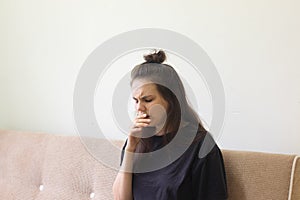 Sick young woman sits at home with a sore throat and coughs