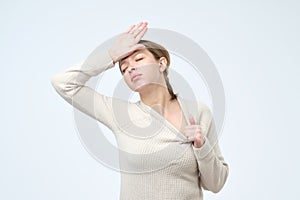 Sickness european woman in gray sweater holding her hand on head feeling ill.