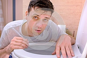 Sickness man vomit in toilet sitting on floor looking at camera having flu.